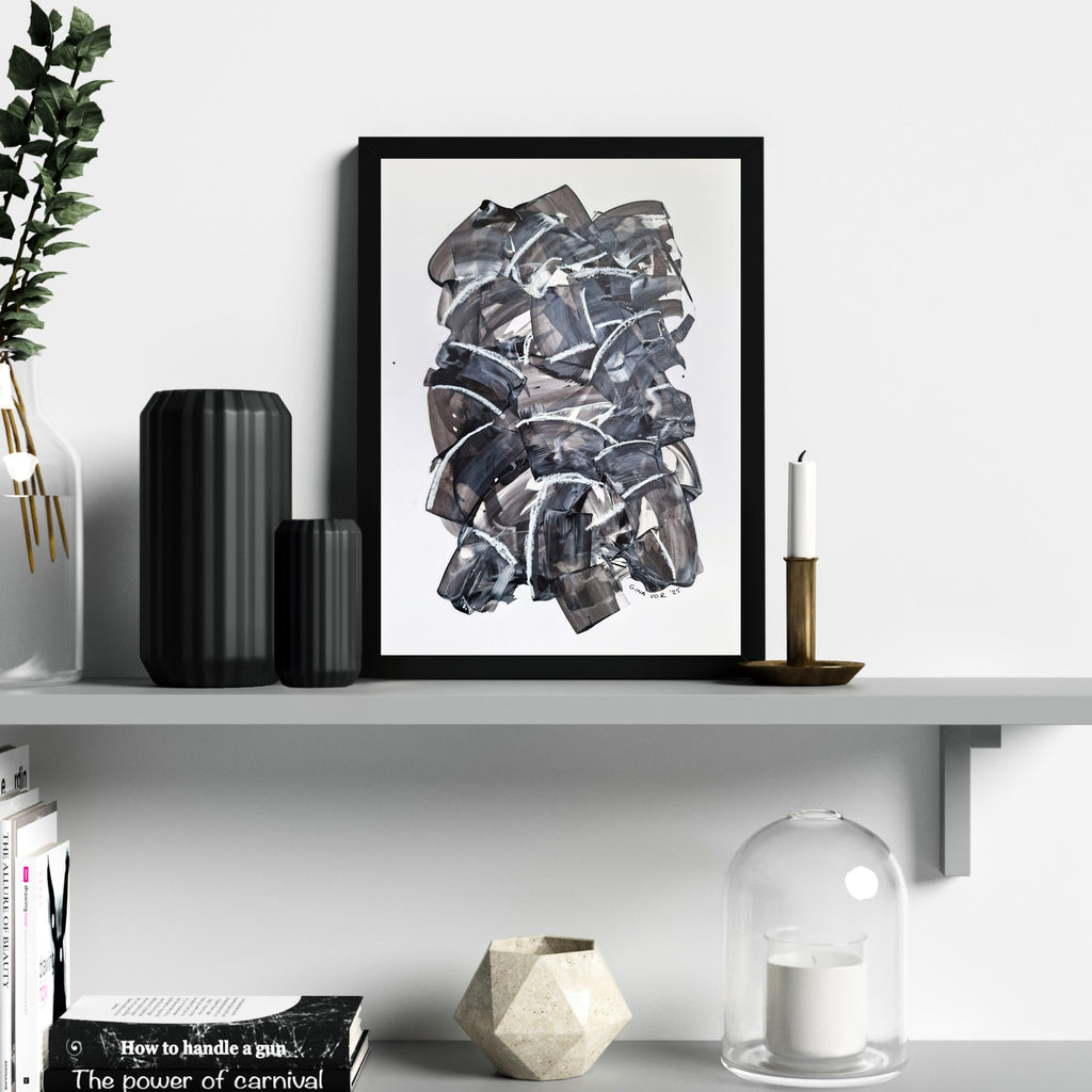 Framed abstract art piece on a shelf with decorative items