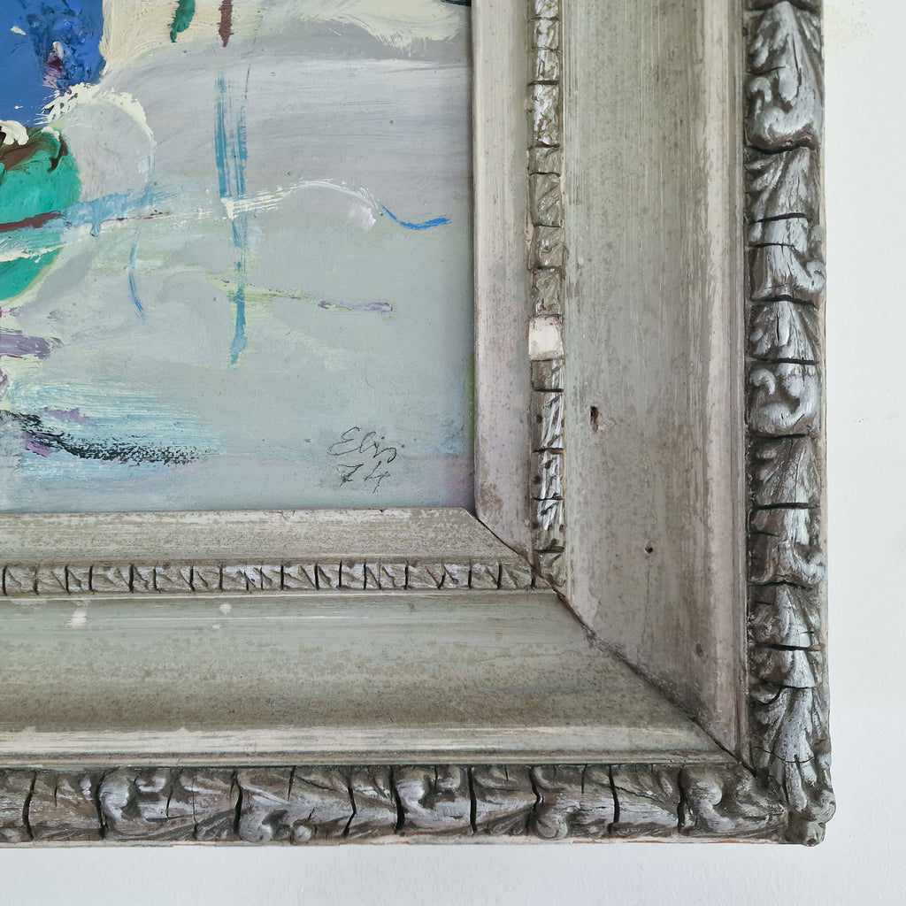 Close-up of an ornate square picture frame with a distressed gray carved wood, showing part of an abstract painting inside with blue, green, and white brushstrokes.