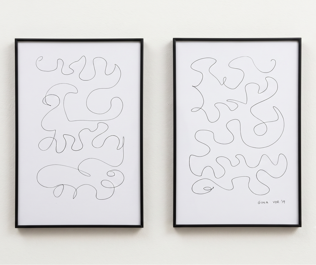 Two framed minimalist abstract line art drawings hanging side-by-side on a white wall. Each print features a single continuous black line drawing on a white background, enclosed in a thin black frame.
