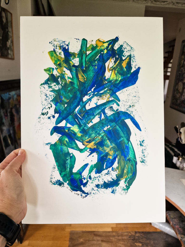 Abstract painting in artist's studio, featuring an abstract, textured painting with splashes of blue, green, and yellow paint on a white background.