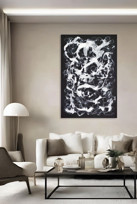 Contemporary living room interior featuring a large abstract black and white painting by artist Gina Vor. The expressive artwork is displayed above a minimalist white sofa, adding contrast and elegance to the neutral-toned decor. The room is styled with modern furnishings, including a sleek coffee table and soft lighting, creating a cozy and sophisticated ambiance