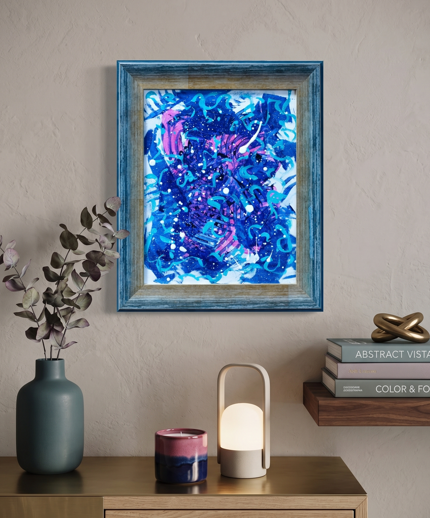 Framed abstract art piece on a wall above a wooden surface with decorative items.