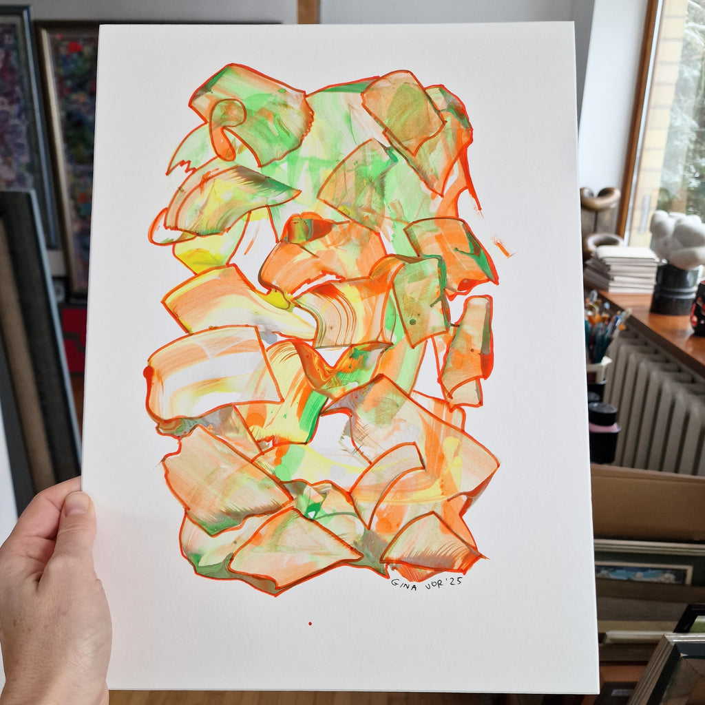 Colorful abstract art on a white sheet held by a hand, with a blurred indoor background.