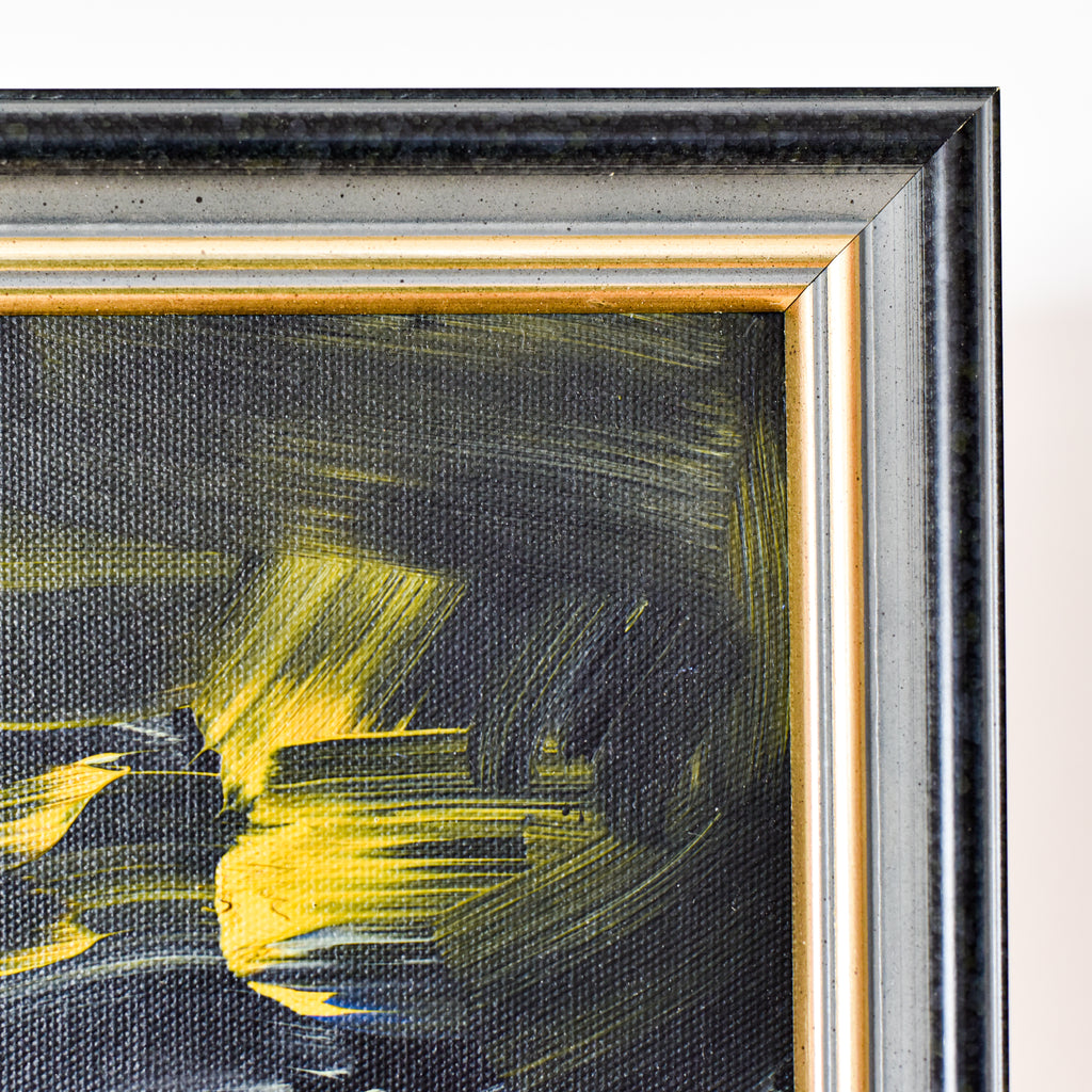 Close-up of a framed abstract painting with yellow and black brushstrokes.