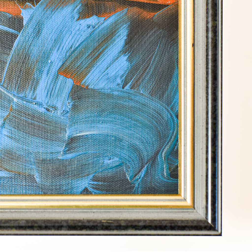 Close-up of an abstract painting with blue and black brushstrokes in a gold frame.
