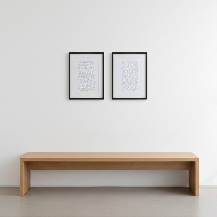 Two minimalist framed black and white abstract line drawings, with white matting, hung side by side on a light gray wall.