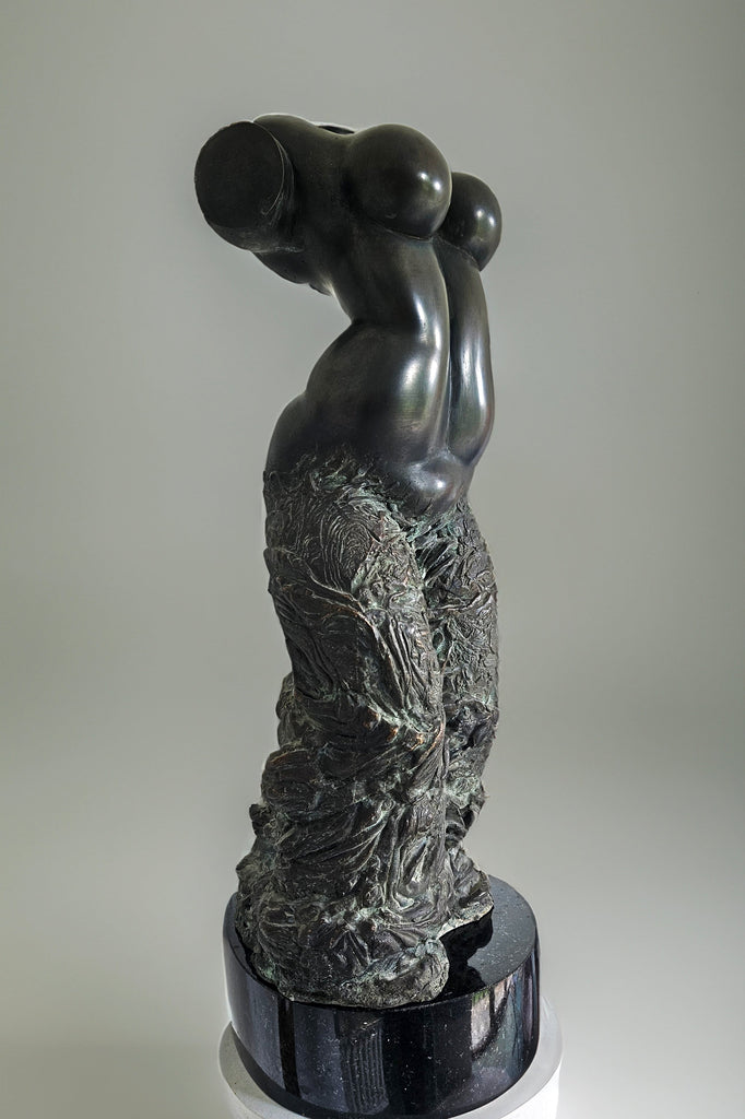 Bronze sculpture of a female dancer's torso by Aloyzas Smilingis-Elis, with smooth curves and intricate detailing on the lower half, standing on a dark base. The sculpture is headless and armless, focusing on the fluid movement and elegance of the dancer's form.