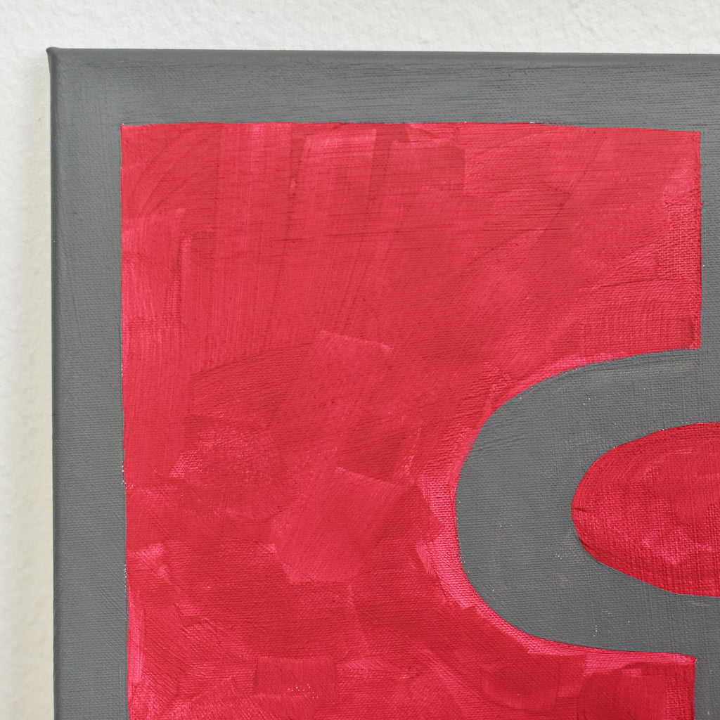 Close-up view of an abstract artwork featuring cool gray and bold red geometric shapes.