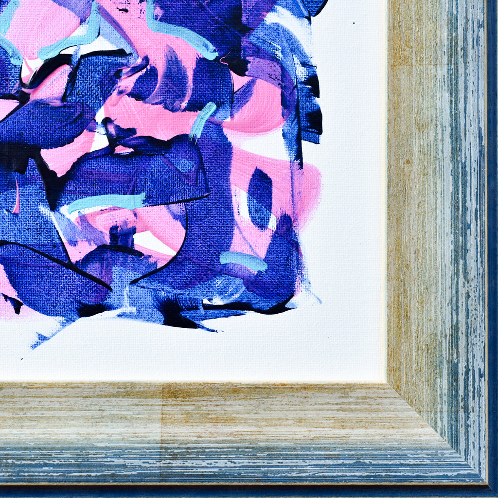 Close-up of a framed abstract painting with blue and pink hues.