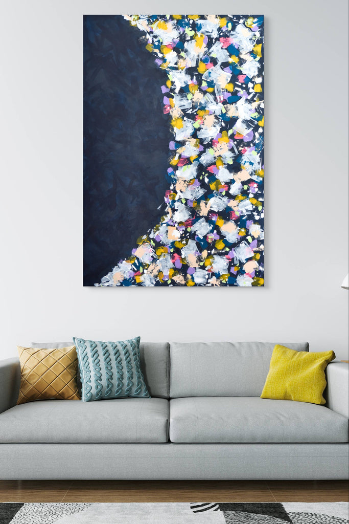 Colorful abstract painting on a wall above a gray sofa with decorative pillows.
